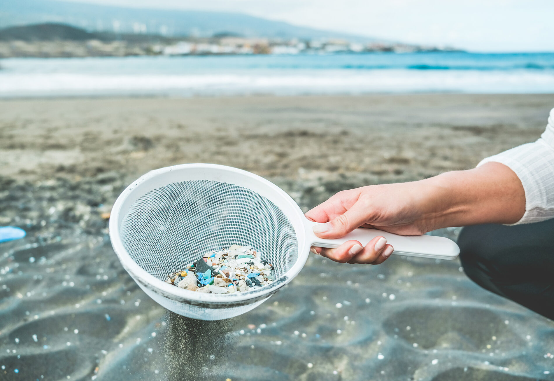 Young woman cleaning microplastic from sand on the beach