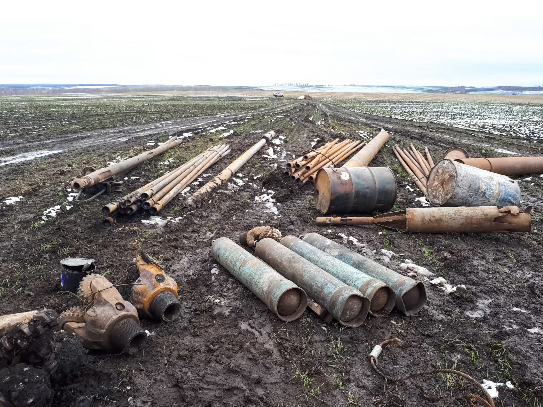 Metal left over from the drilling of a well in the tundra, including barrels, cylinders and chisel balls