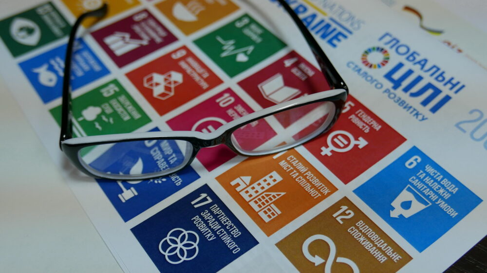 Printout of Sustainable Development Goals in Ukrainian with pair of glasses on top