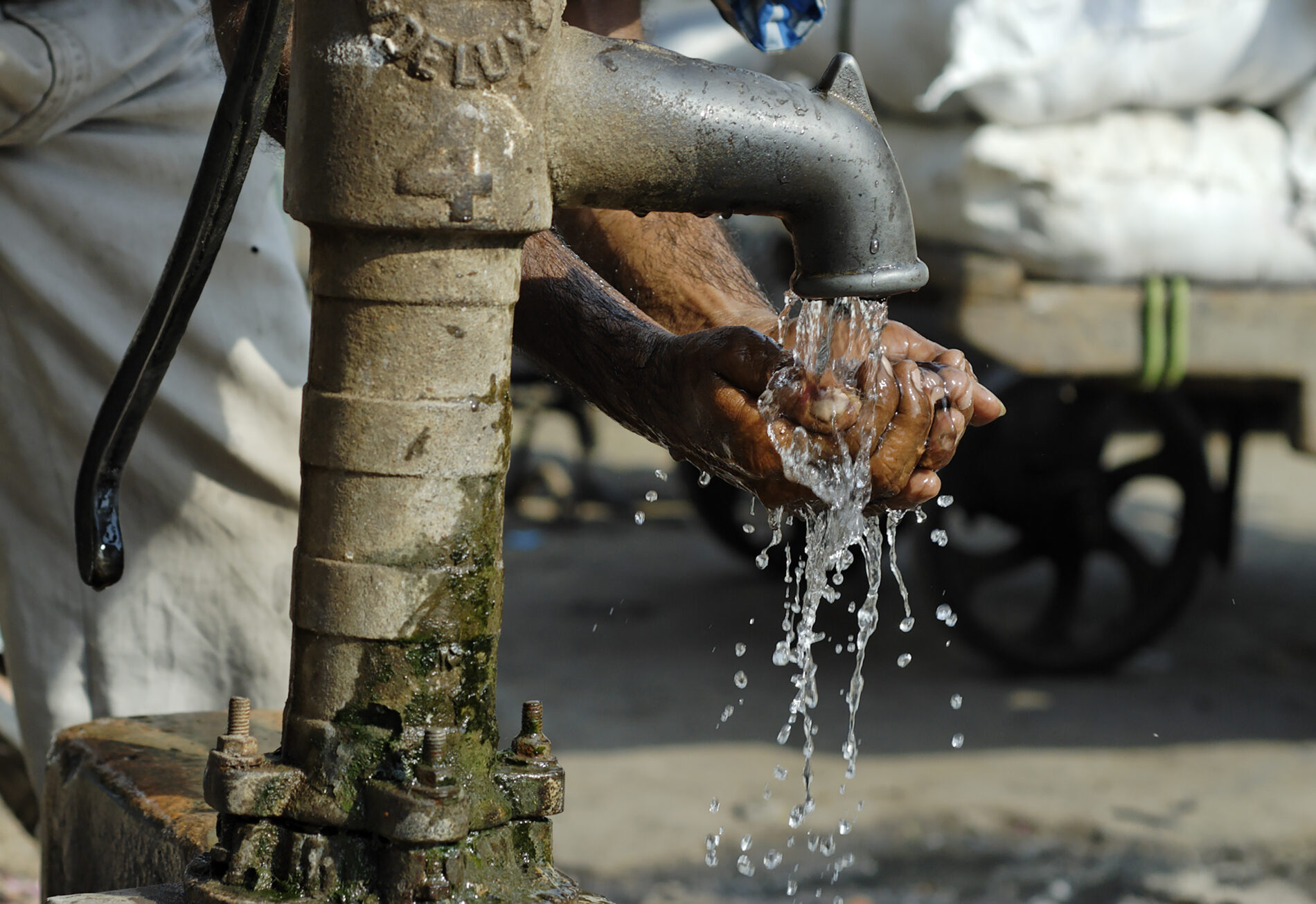 Man washing his hands at an old-fashioned water pump, street scene in Old Delhi
