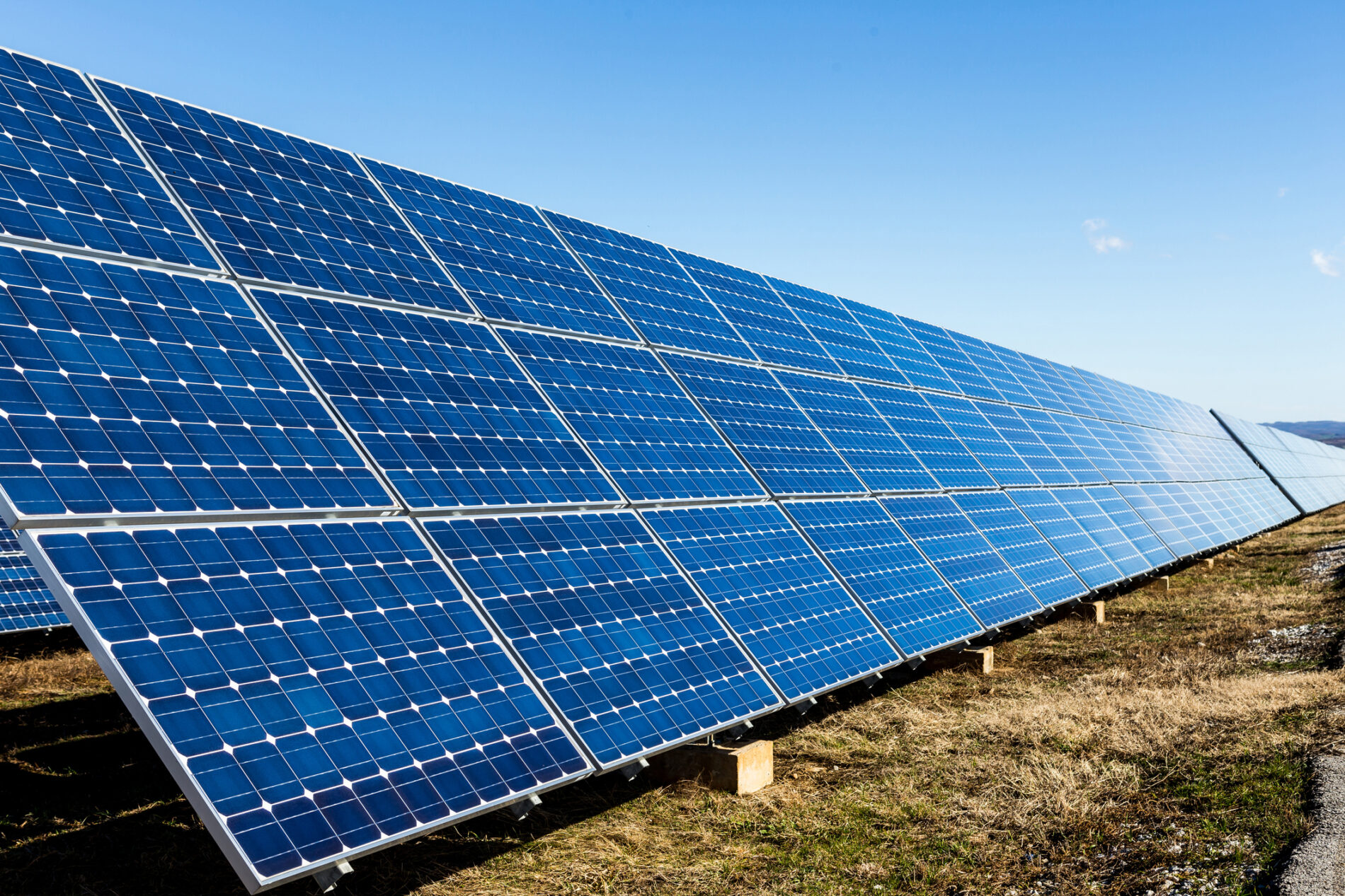 Row of blue photovoltaic solar panels and blue sky with clouds