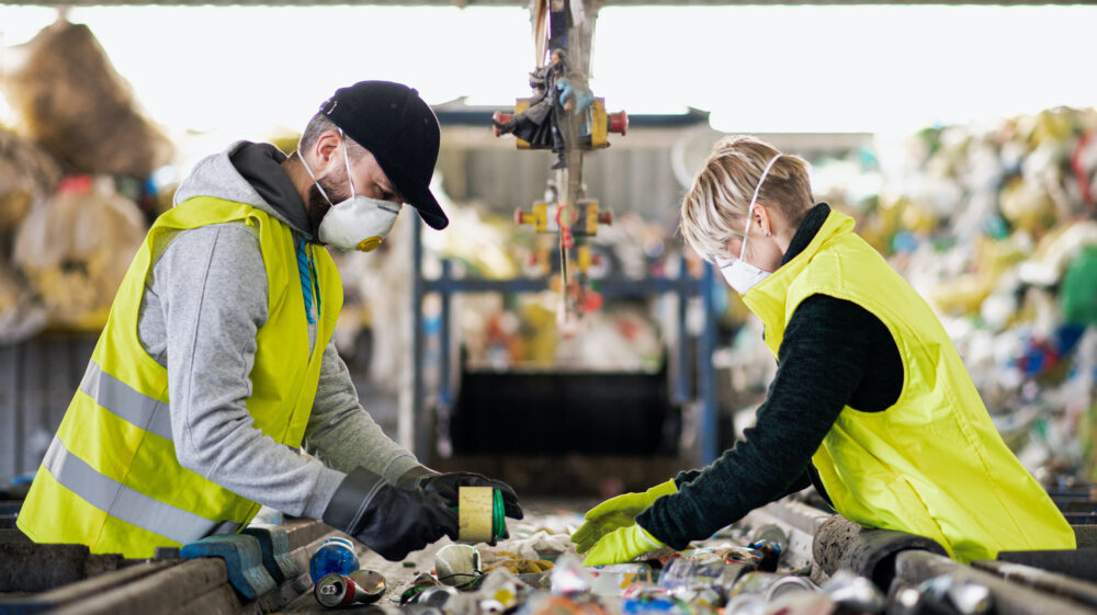 Male and female workers with protective face masks at landfill, Slovakia