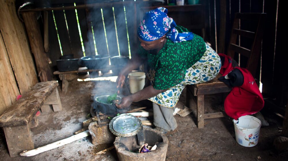 African woman cooking food over wood-burning fire, Nanyuki, Kenya