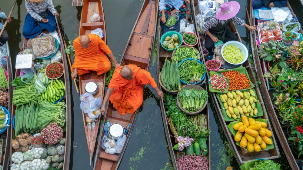Aerial view of Damnoen Saduak Floating Market or Amphawa. Local people and monks in orange robes sell fruits, traditional food on boats in canal, Ratchaburi District, Thailand