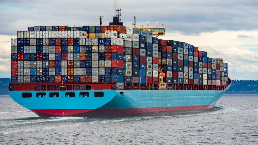 Blue and red cargo ship at sea during daycare filled with containers