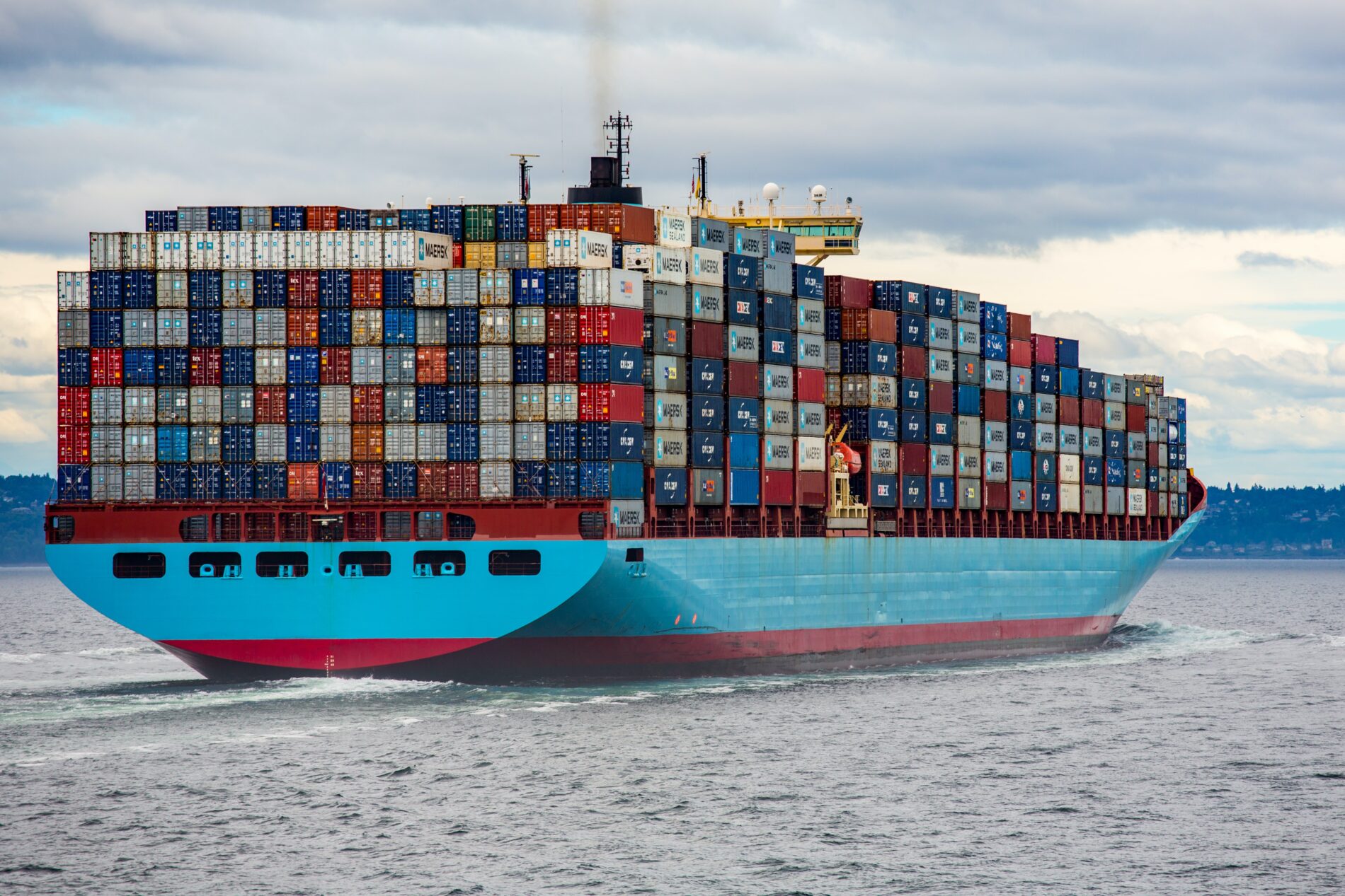 Blue and red cargo ship at sea during daycare filled with containers