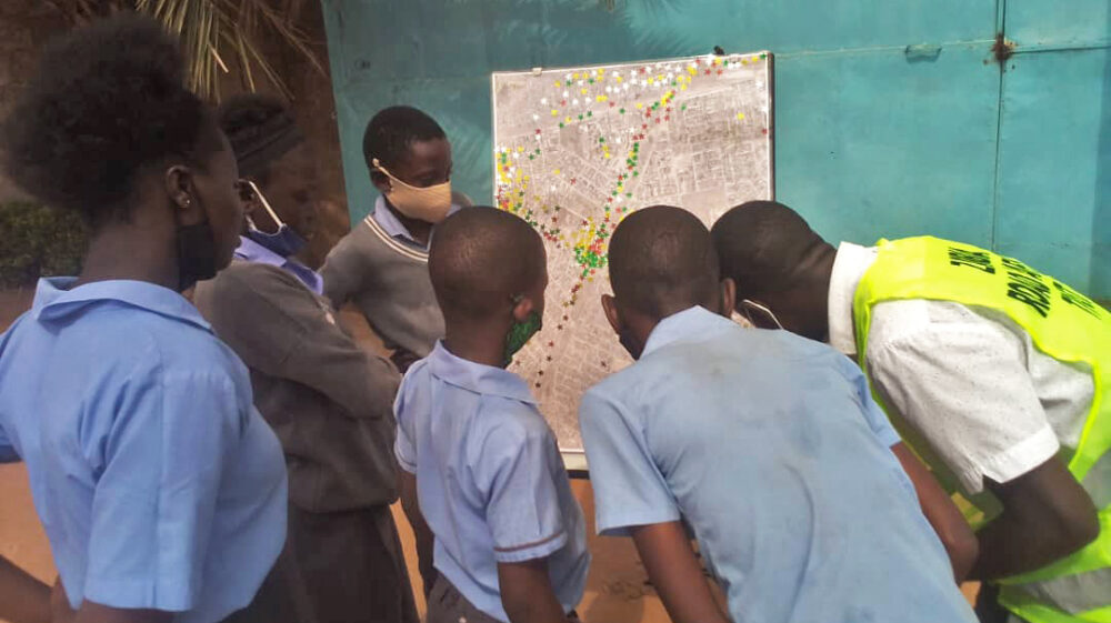 Schoolchildren in Lusaka, Zambia looking at a map of transport hotspots