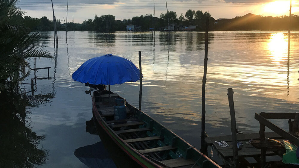 Rowboat with blue umbrella at sunset, Pak Phanang River, Baan Koh Chai, southern Thailand