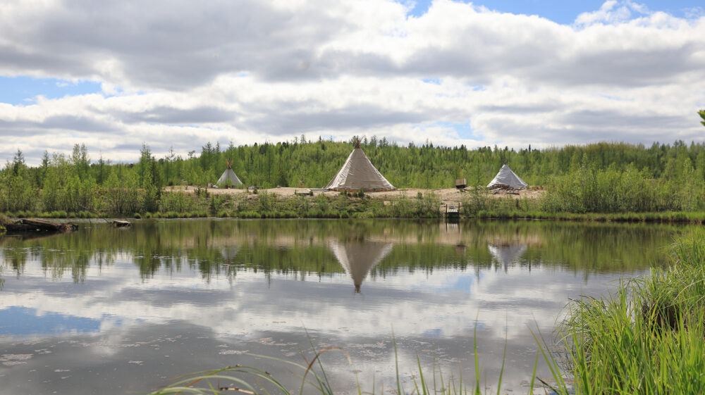 Summer landscape with reflection of Nenets dwelling in water, northern Siberia, Russia