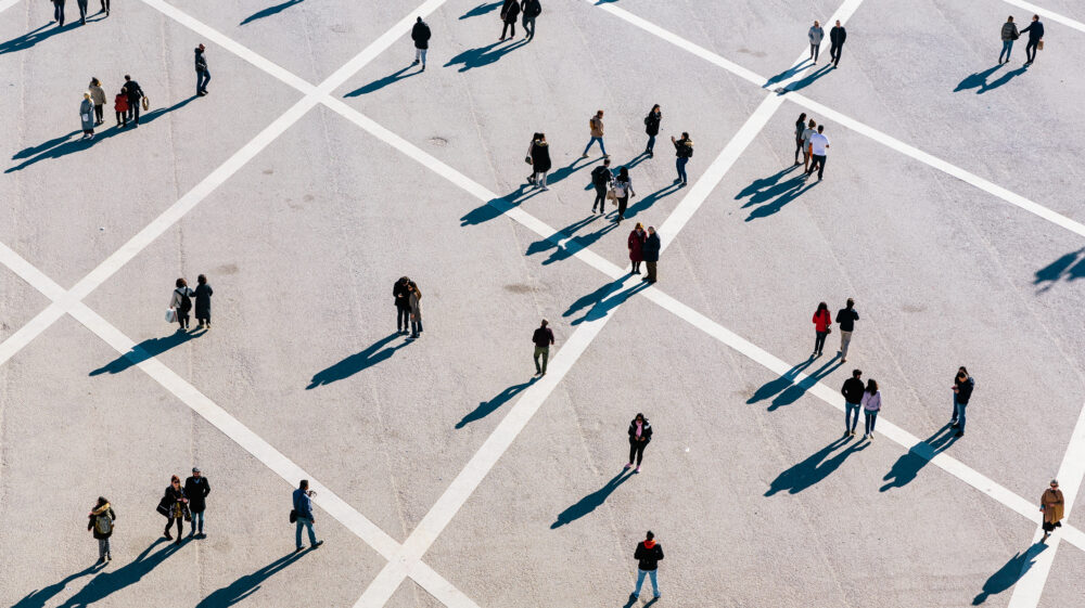 Aerial view of people walking across town square on sunny day in jackets, Lisbon, Portugal