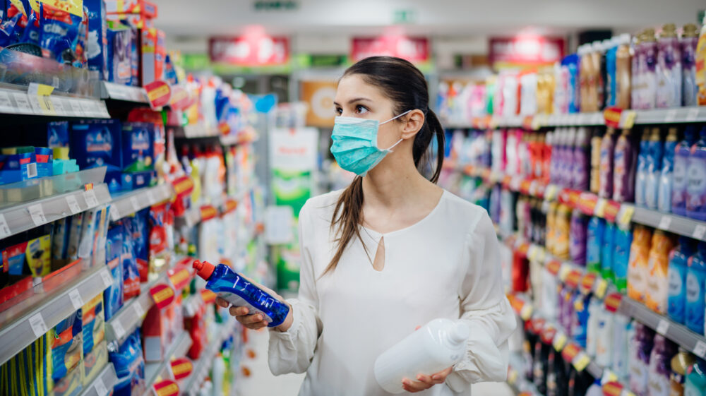 Woman wearing face mask shopping for household cleaning products