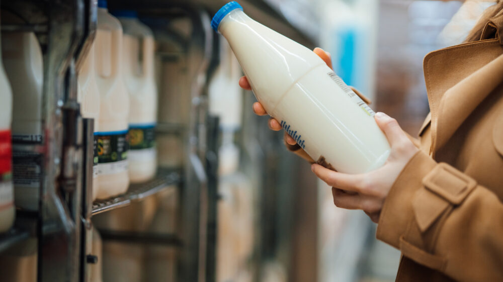 Close up shot of woman holding a bottle of organic unsweetened almond milk in supermarket, London, UK