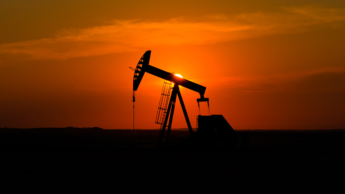 Oil rig platform at sunset with bright sun and orange sky, Canada