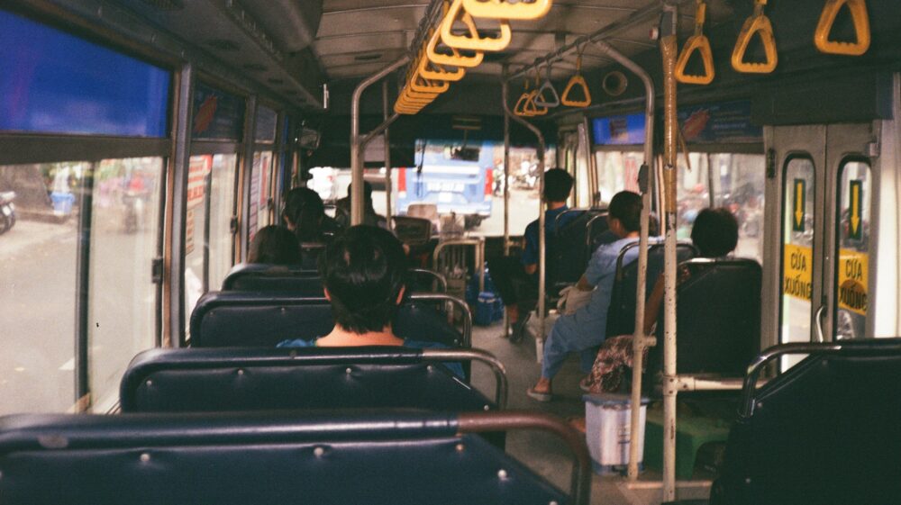 Passengers riding half-empty bus in daytime with dark blue seats, Ho Chi Minh City, Vietnam