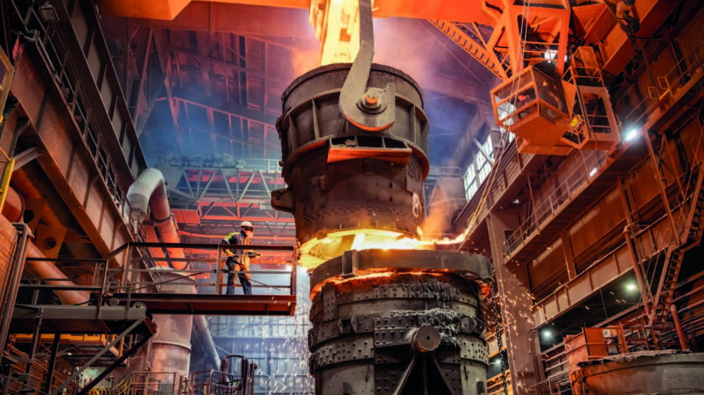 Steelworker starting molten steel pour in steelworks, UK