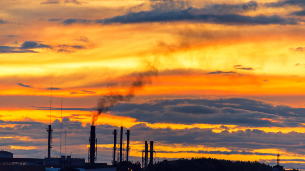 Smokestacks from factory in distance under cloudy skies at dusk, Iquitos, Peru