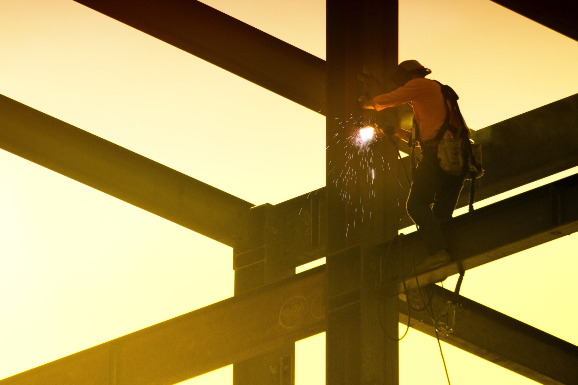 Welder working on beam at construction site at sunrise