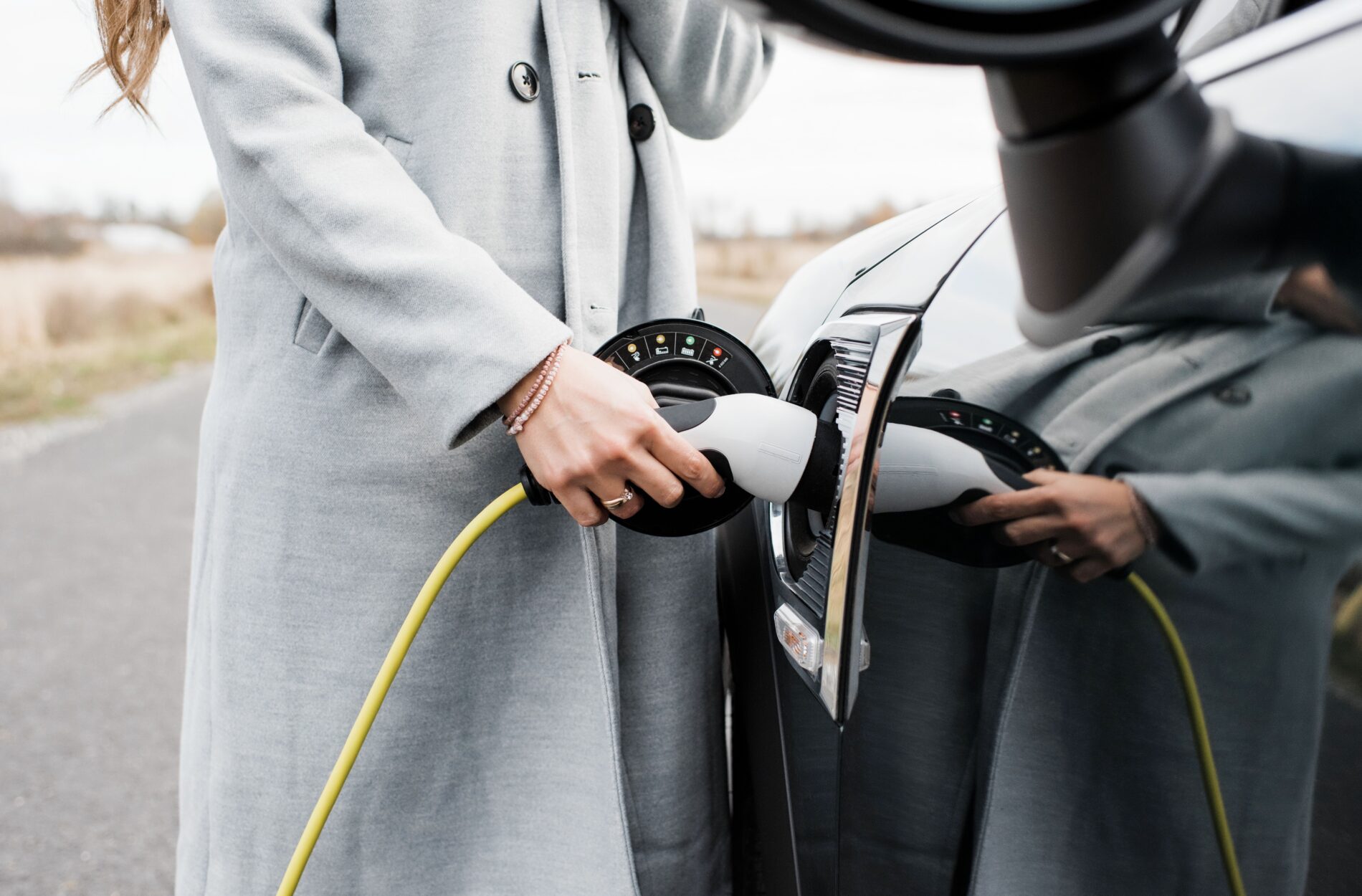 Close-up of woman's hand plugging in charger to electric car, Stockholm, Sweden