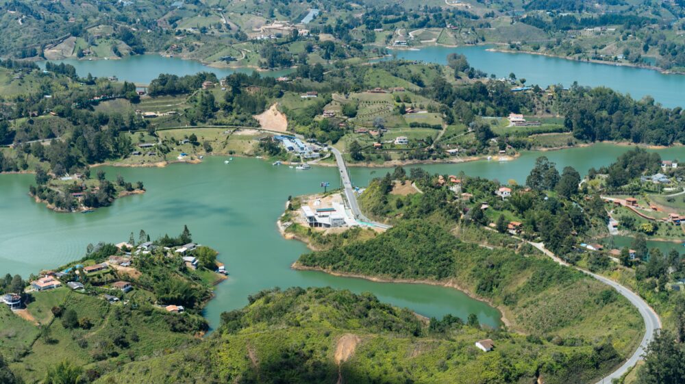Aerial view of curved road heading towards bridge with islets srrounded by green water, El Peñón de Guatapé, Colombia