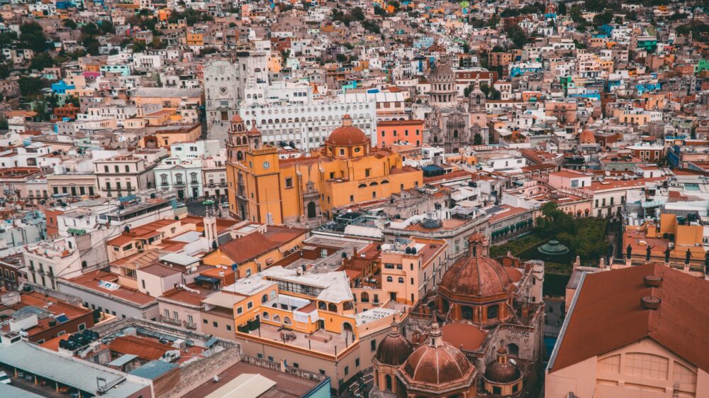 Aerial view of Guanajuato, Mexico with white and orange-coloured colonial-era buildings, including churches, hotels and houses