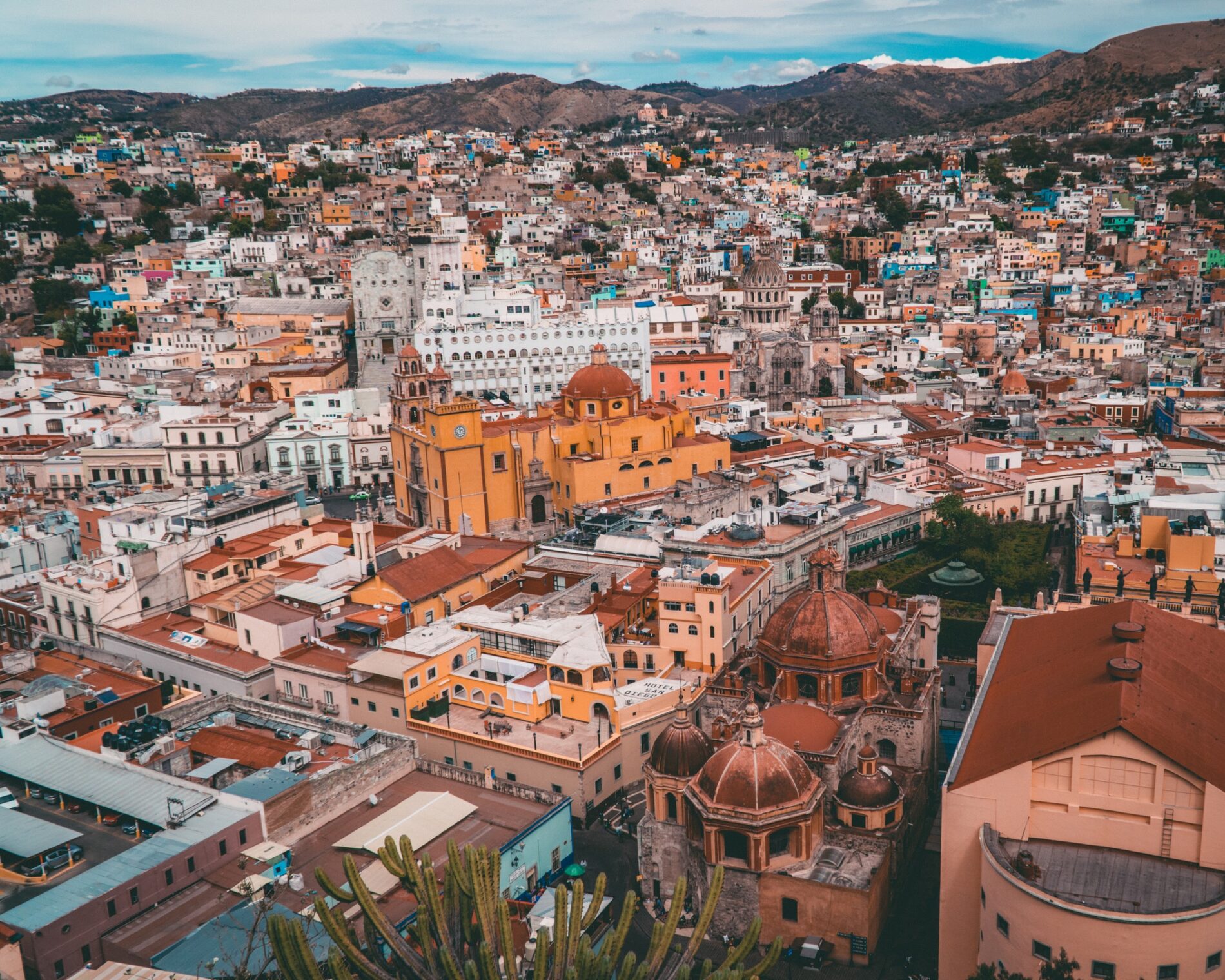 Aerial view of Guanajuato, Mexico with white and orange-coloured colonial-era buildings, including churches, hotels and houses