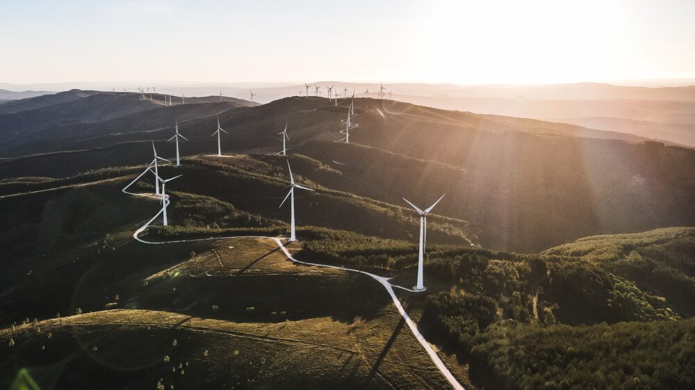 Aerial view of white wind turbines dotting green hilltops, Parque Eólico, Serra da Lousã Portugal, March 2021