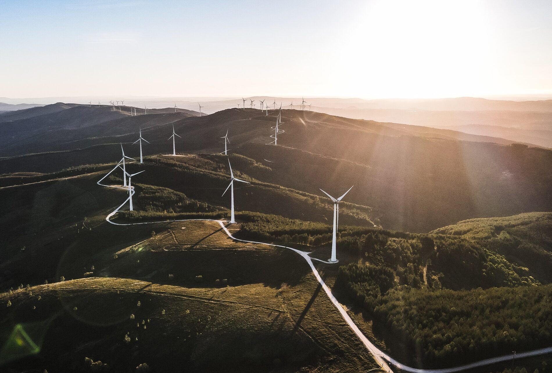 Aerial view of white wind turbines dotting green hilltops, Parque Eólico, Serra da Lousã Portugal, March 2021