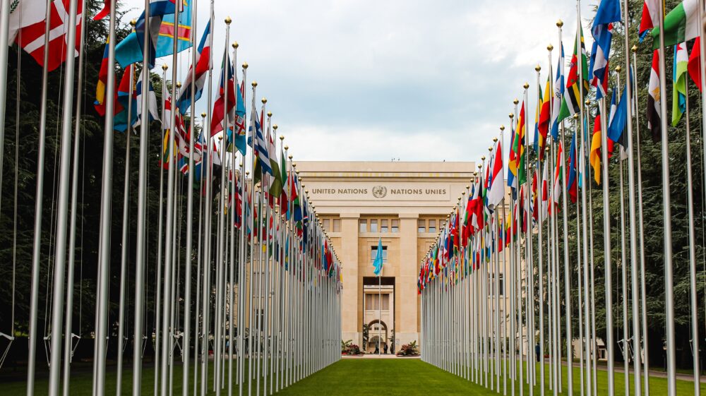 Flags of UN line grass in front of UN building, Geneva, Switzerland