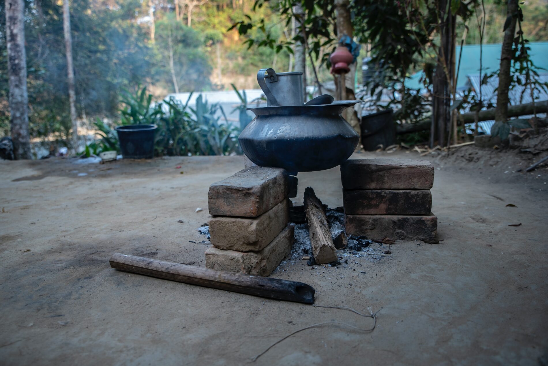 Black clay pot suspended over wood-burning fire, cooking in rural area of Bandarban, Bangladesh