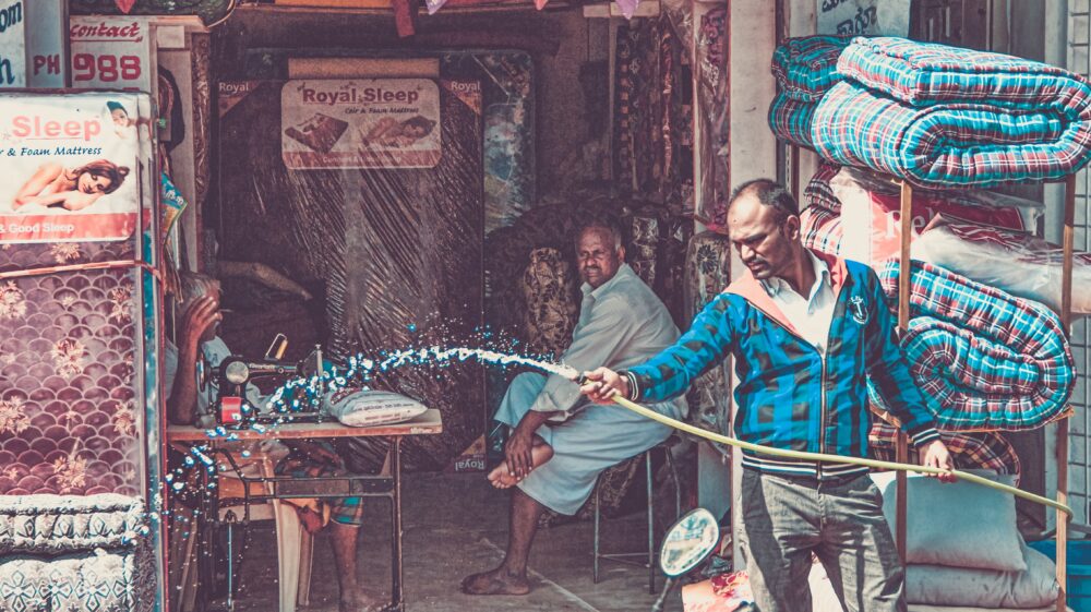 Man hoses down mattress storefront, Yelahanka New Town, Bengaluru, India
