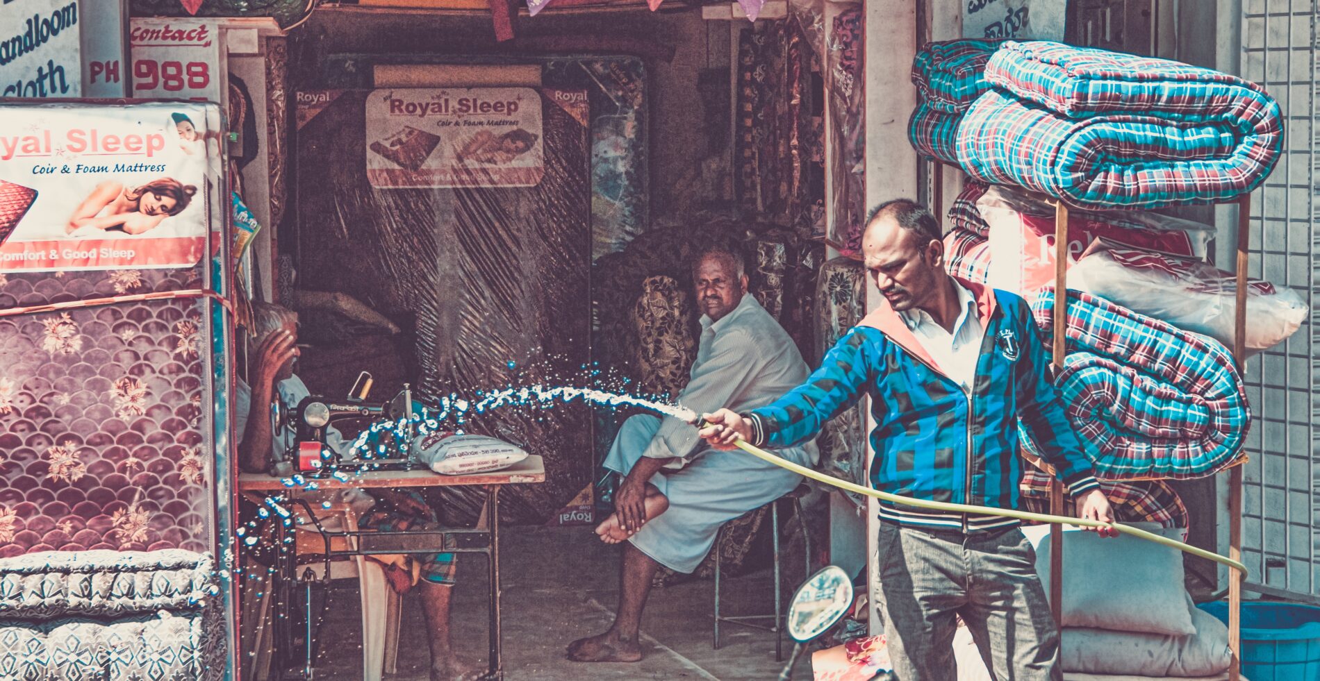 Man hoses down mattress storefront, Yelahanka New Town, Bengaluru, India