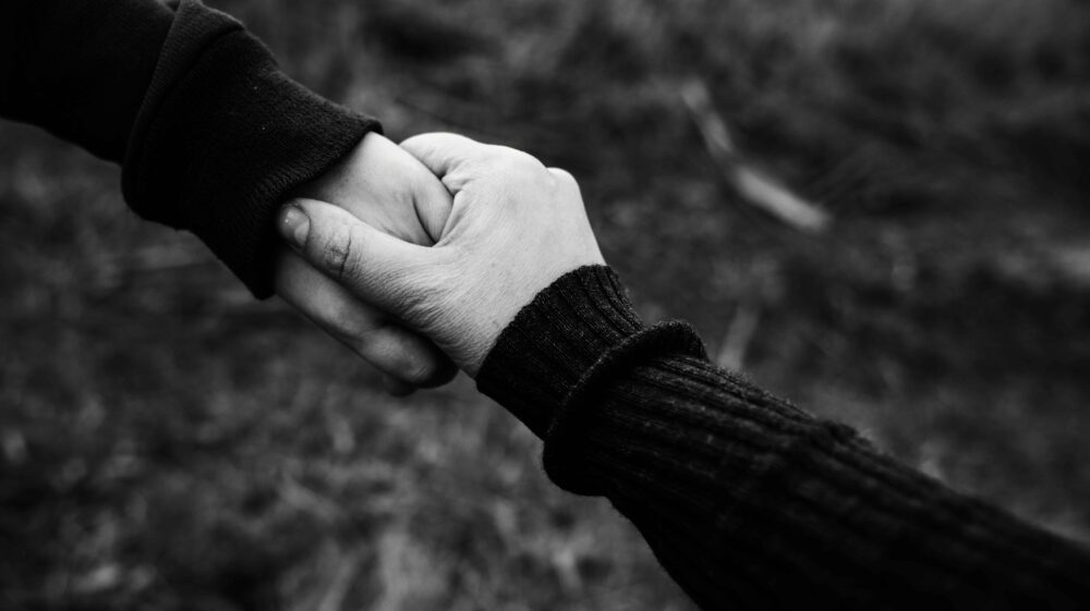 Two people holding hands. Photo by PIXNIO