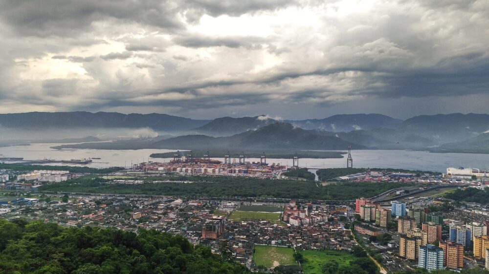 Town with factories and residential buildings with river and mountains in background under overcast sky, Brazil