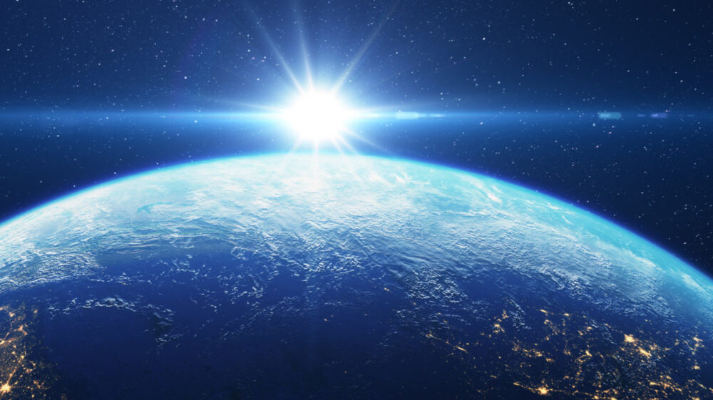 Bright light in space above Earth with stars in background