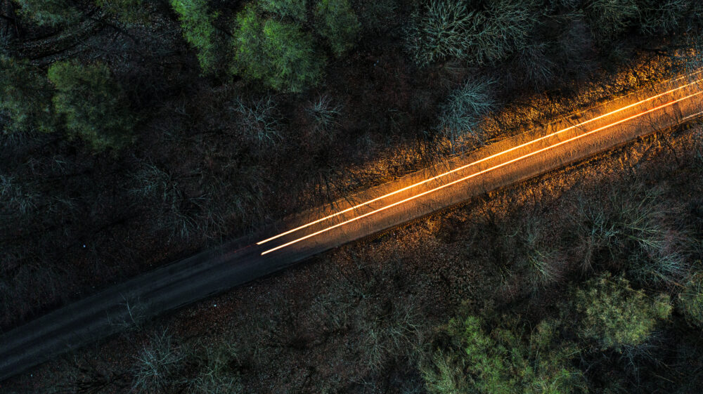 Drone view above a road through a forest at night