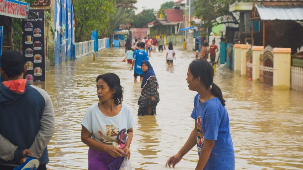 Residents wade in knee-high water on street, Indonesia