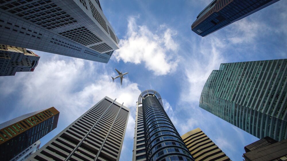 Skyscrapers and aeroplane flying above taken from ground up, Singapore