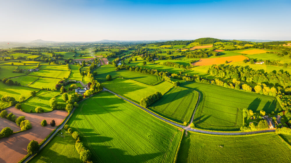 Aerial panorama over green summer farm fields crops pasture
