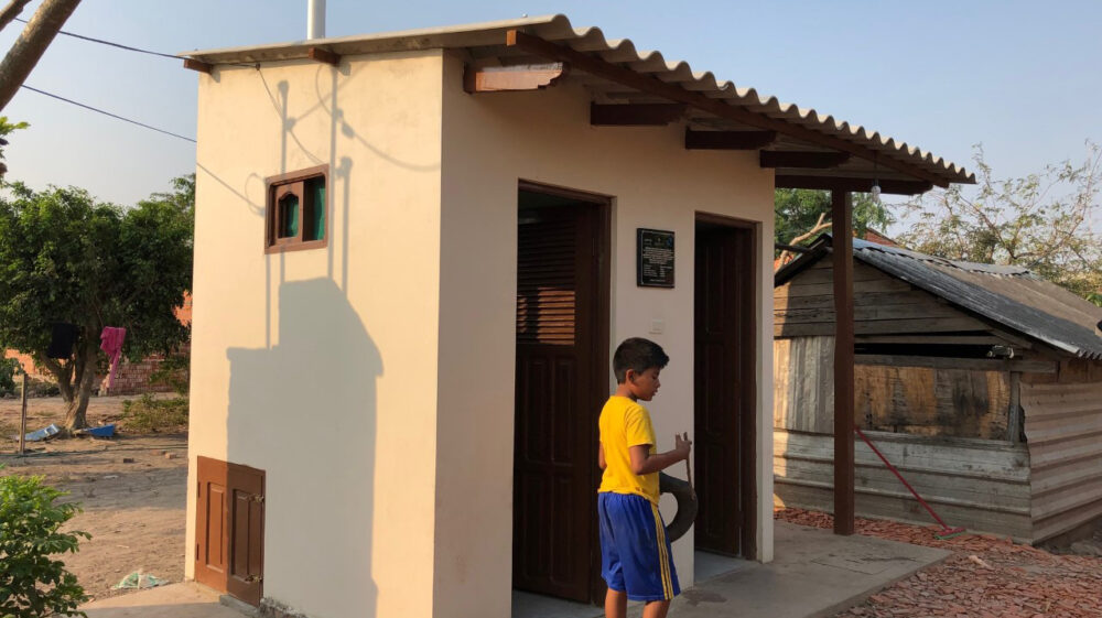 Child outside latrine in Montero, Bolivia