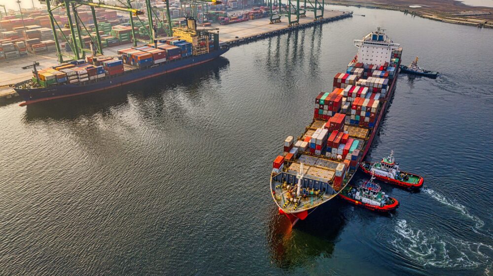 Red and blue cargo ships floating next to dock