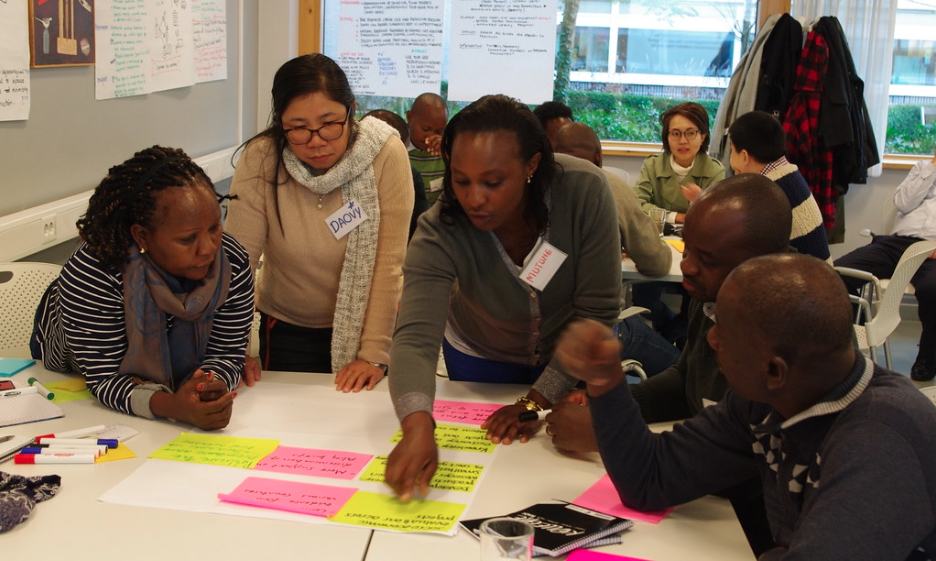 Participants from Asia and Africa at workshop on co-development at table with neon yellow and pink Post-It notes