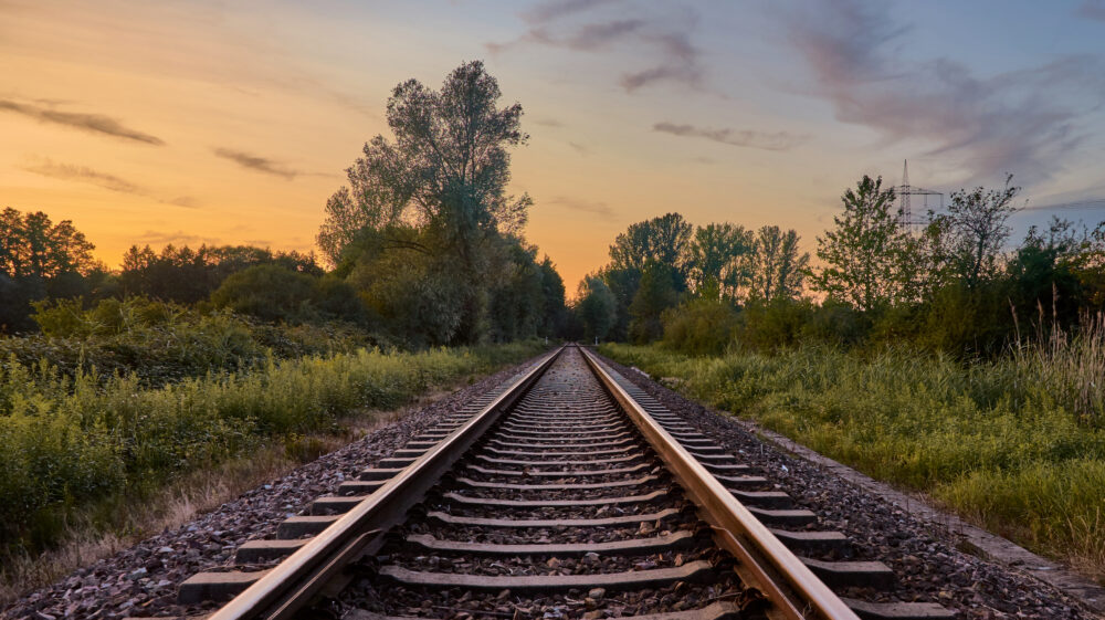 Train tracks in front of grassy fields, trees and sunset sky, Rastatt, Baden-Württemberg, Germany. symbolizing circular economy policy