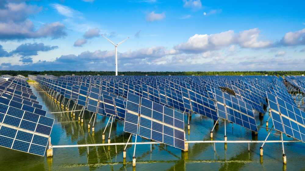 Solar panels installed in fish pond with tall wind turbine in distance under blue sky with white and grey clouds. Yancheng, Jiangsu, China towards multifunctionality: nature society dichotomy, nature, adaptation, climate, landscape