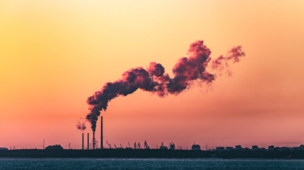 Industrial chimneys emitting smoke in the sunset