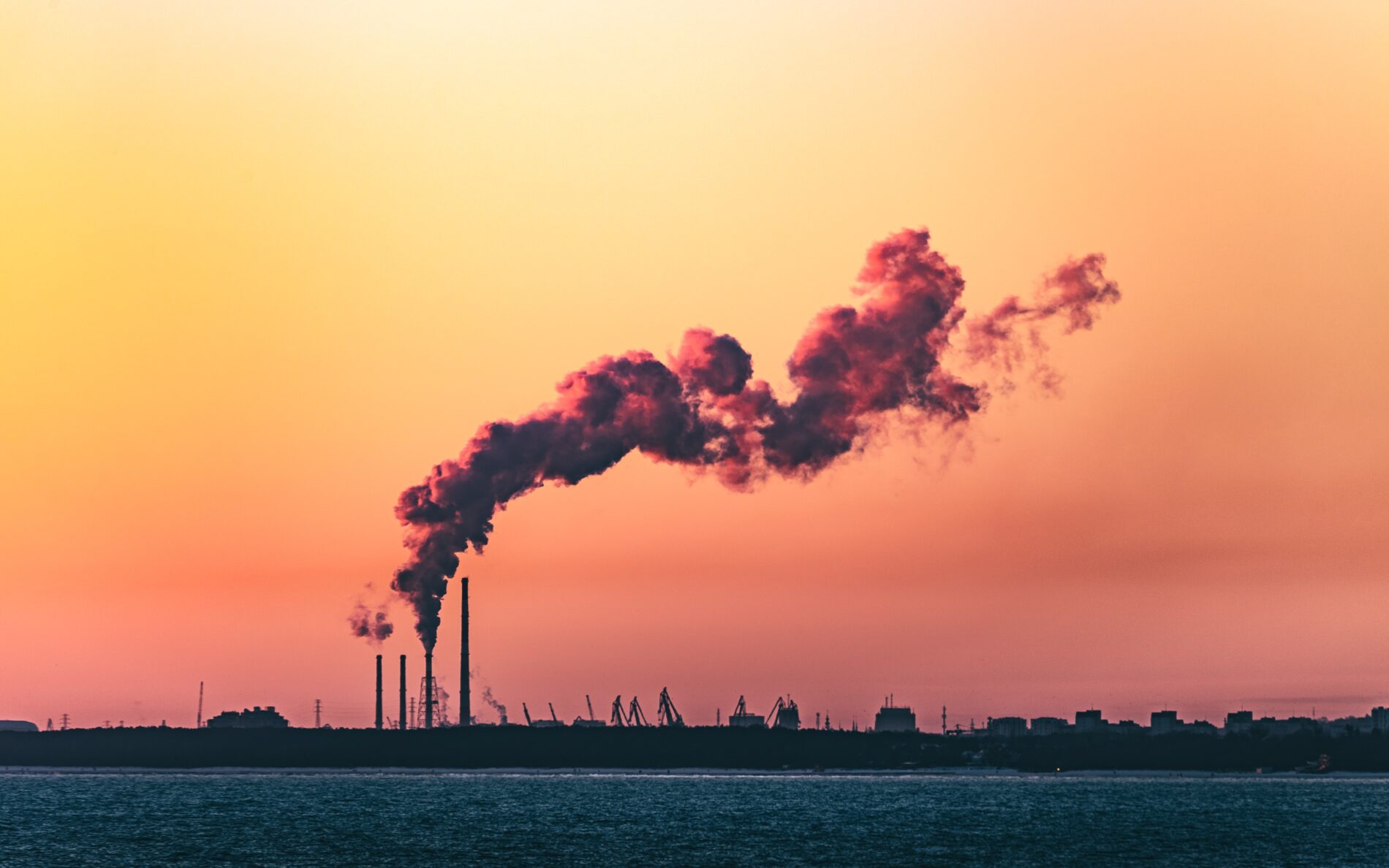 Industrial chimneys emitting smoke in the sunset