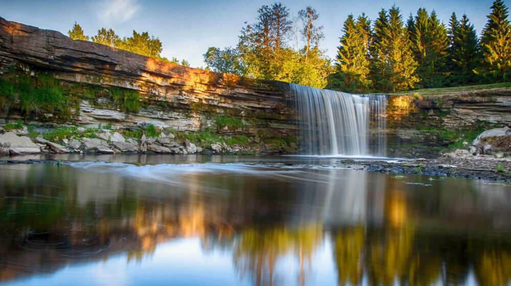 Scenic view of waterfall under blue sky In forest, Jägala Waterfall, Estonia