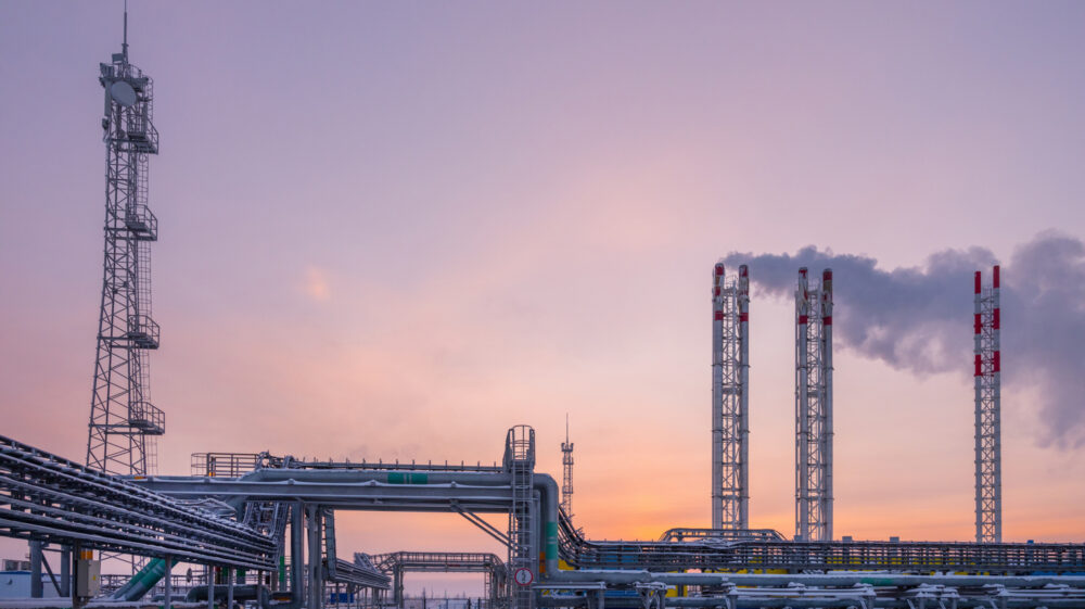 Russian gas production and processing facility works under blanket of snow at dawn and cloudy purple and pink sky, Novy Urengoi, Russia