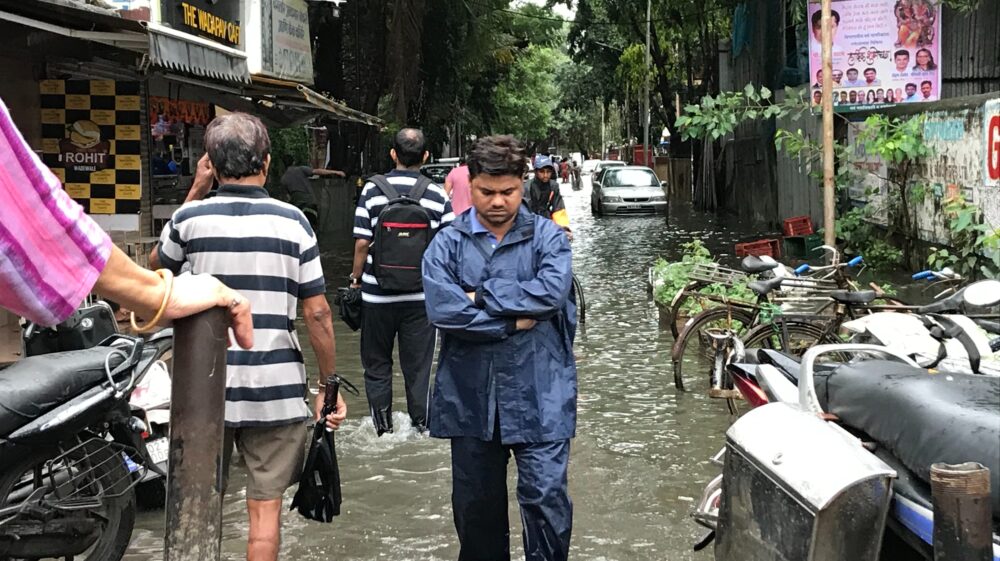 Residents walking down flooded street, Mumbai, India