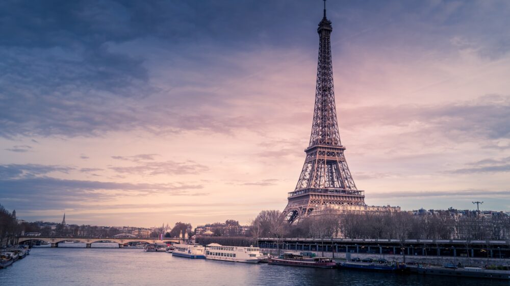 The Eiffel Tower and Seine River at dusk under cloudy purple sky from the northwest, Paris, France