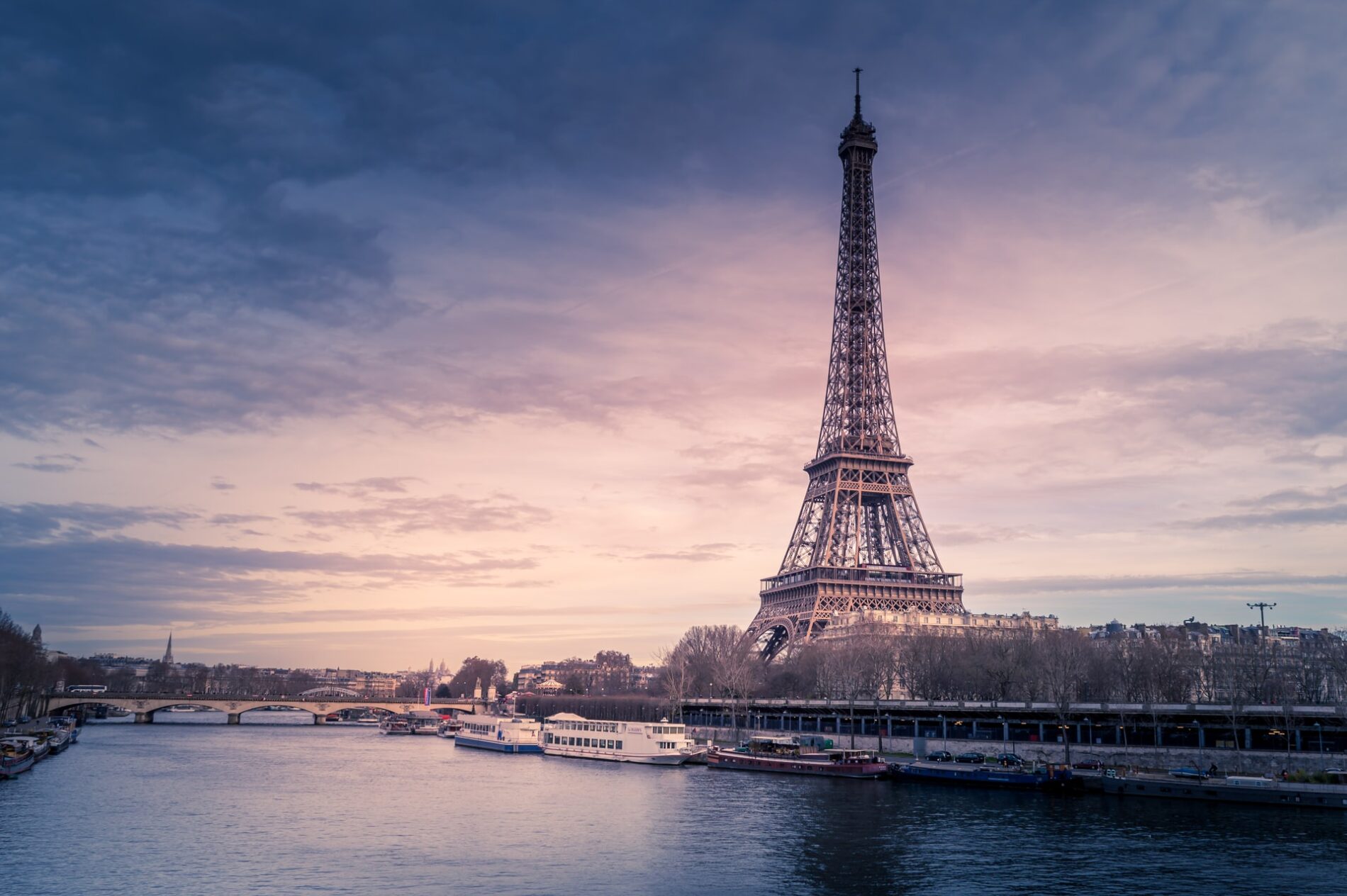 The Eiffel Tower and Seine River at dusk under cloudy purple sky from the northwest, Paris, France